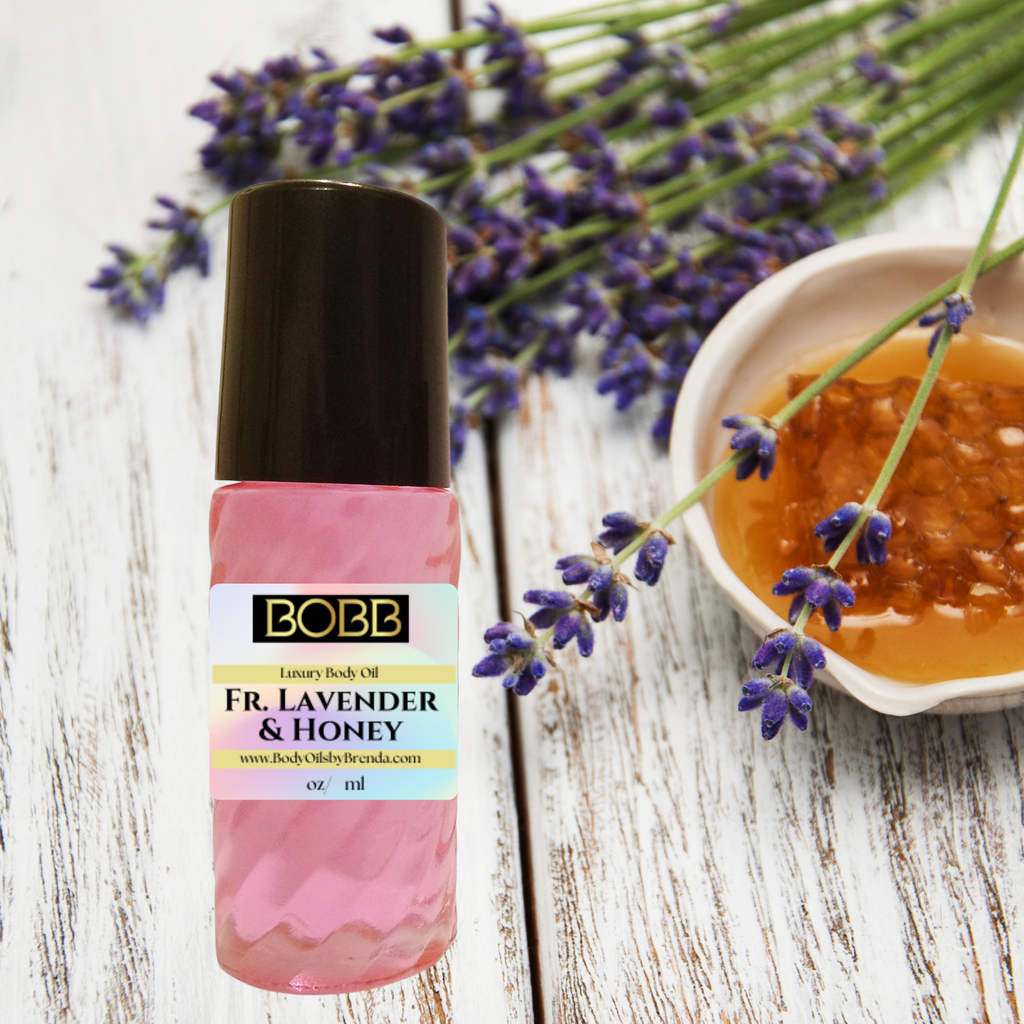 A bottle of BOBB body oil labeled 'Fr. Lavender & Honey' stands on a white wood surface beside lavender sprigs and a small dish of honey.